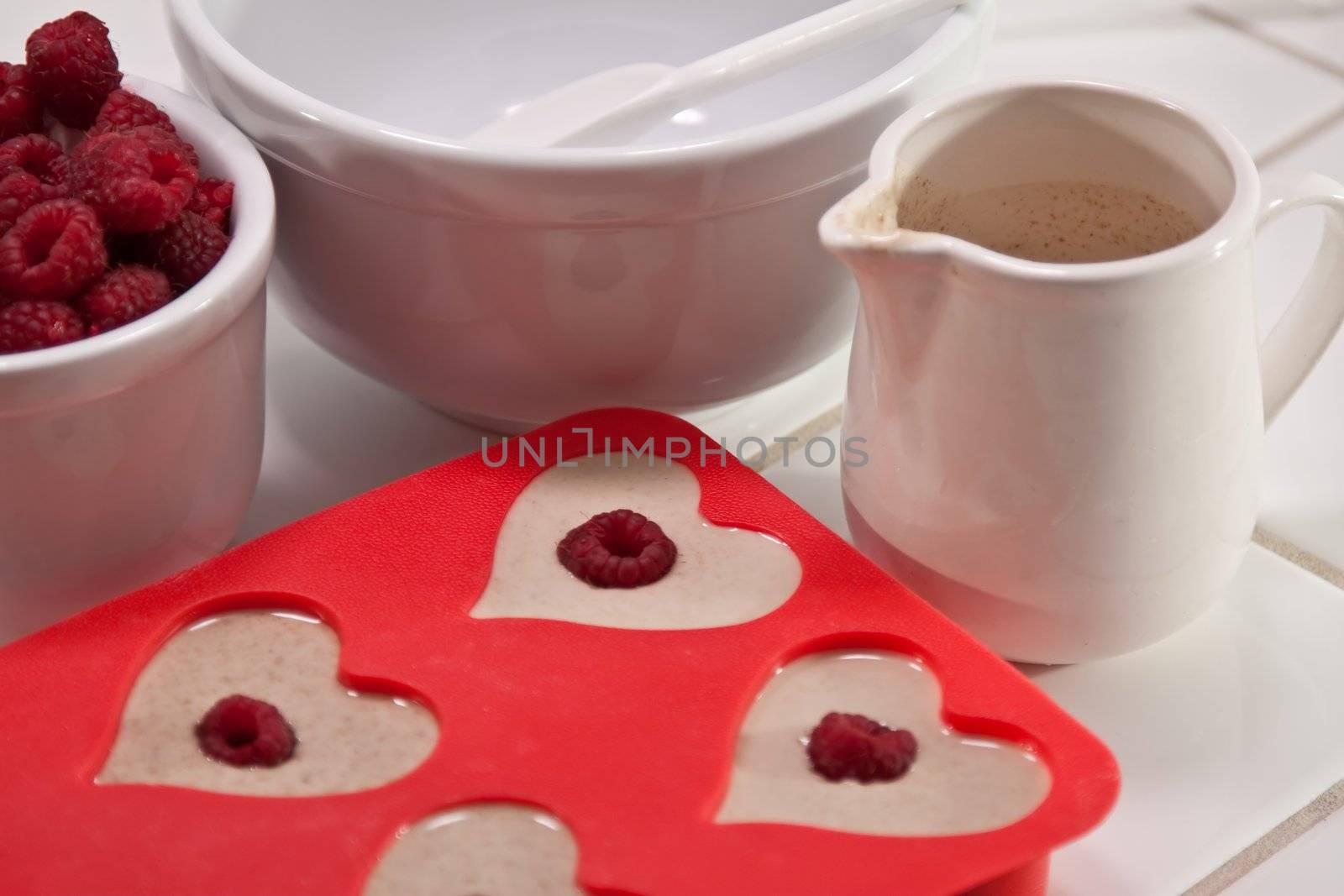 Batter bowl and raspberries with heart shaped muffin pan