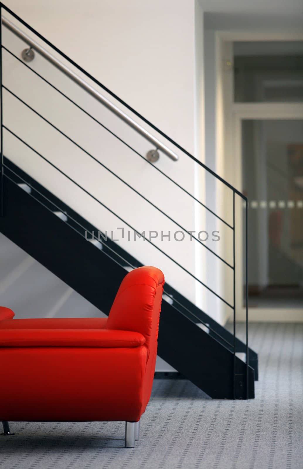 Metal stairs above  red sofa in minimalistic interior
