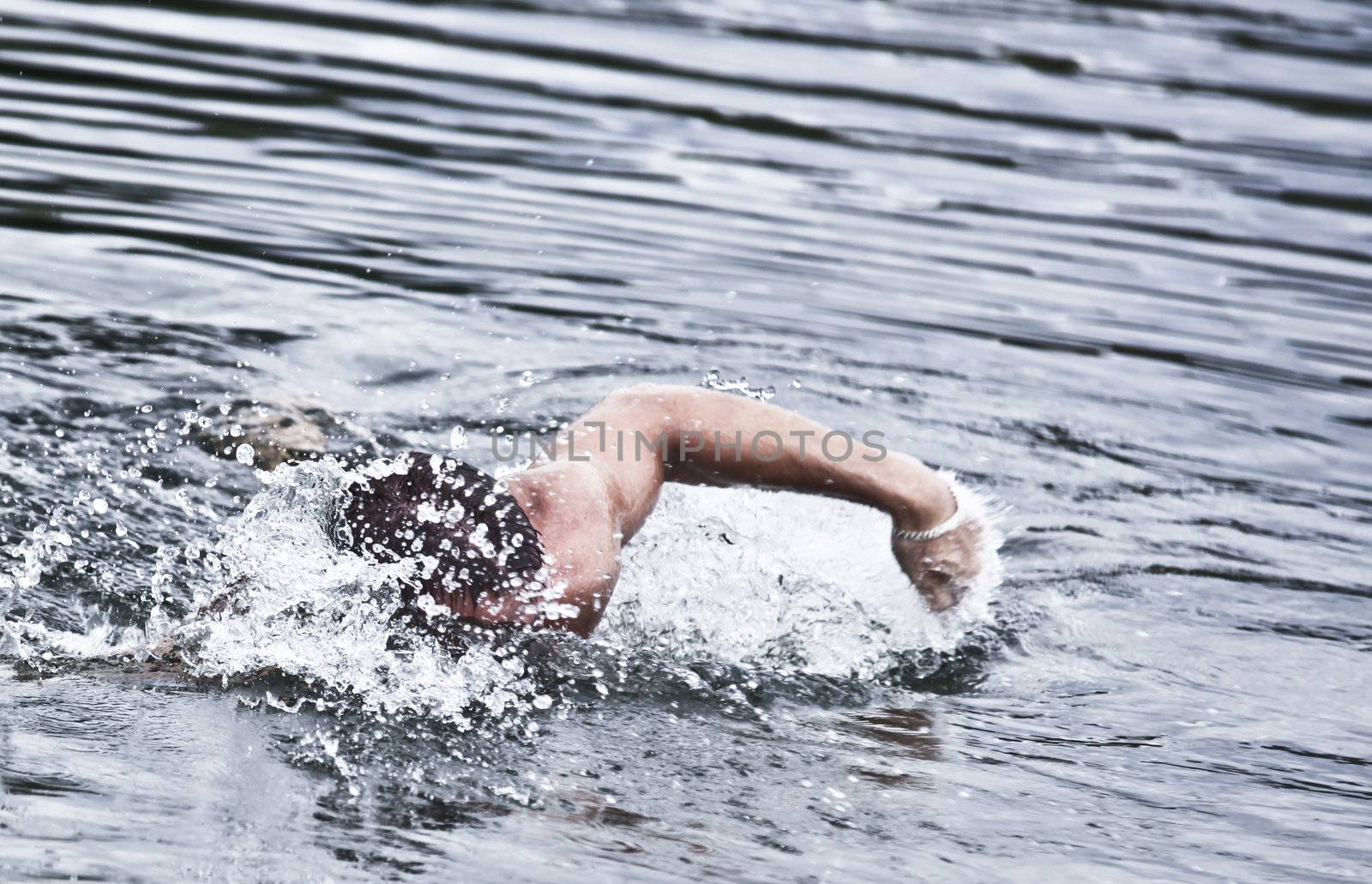 Photo Of A Man Swimming With Passion And Creating Splashes Of Water