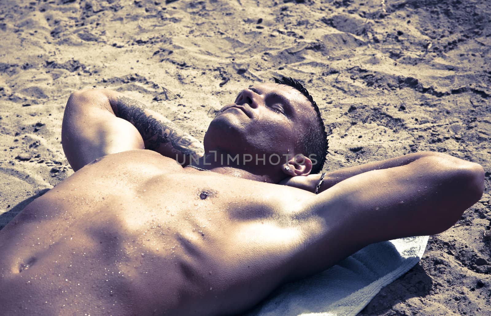 Young Handsome Man Resting On The Sand After A Swim