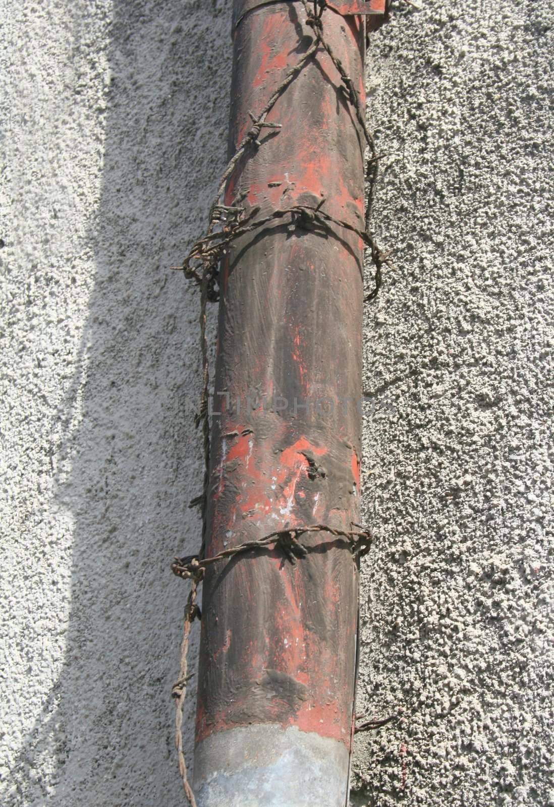 Rusty rain pipe with barbed wire