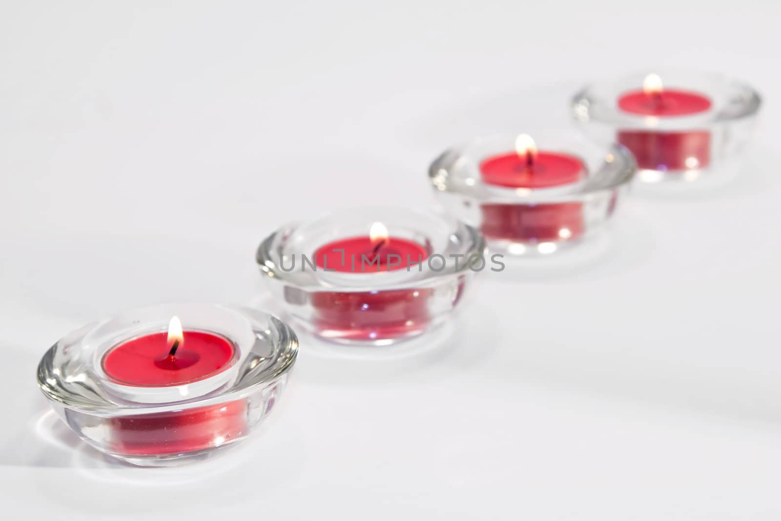 Line of red lit candles on white background