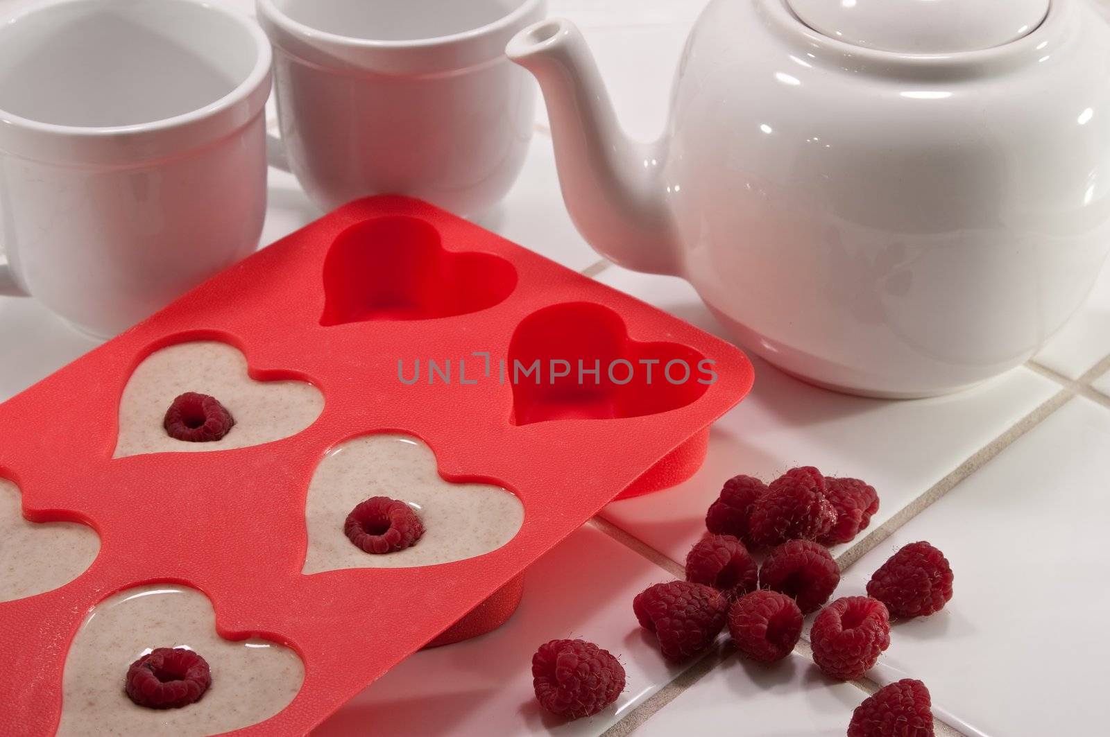Heart shaped muffin pan with tea cups and pot with raspberries