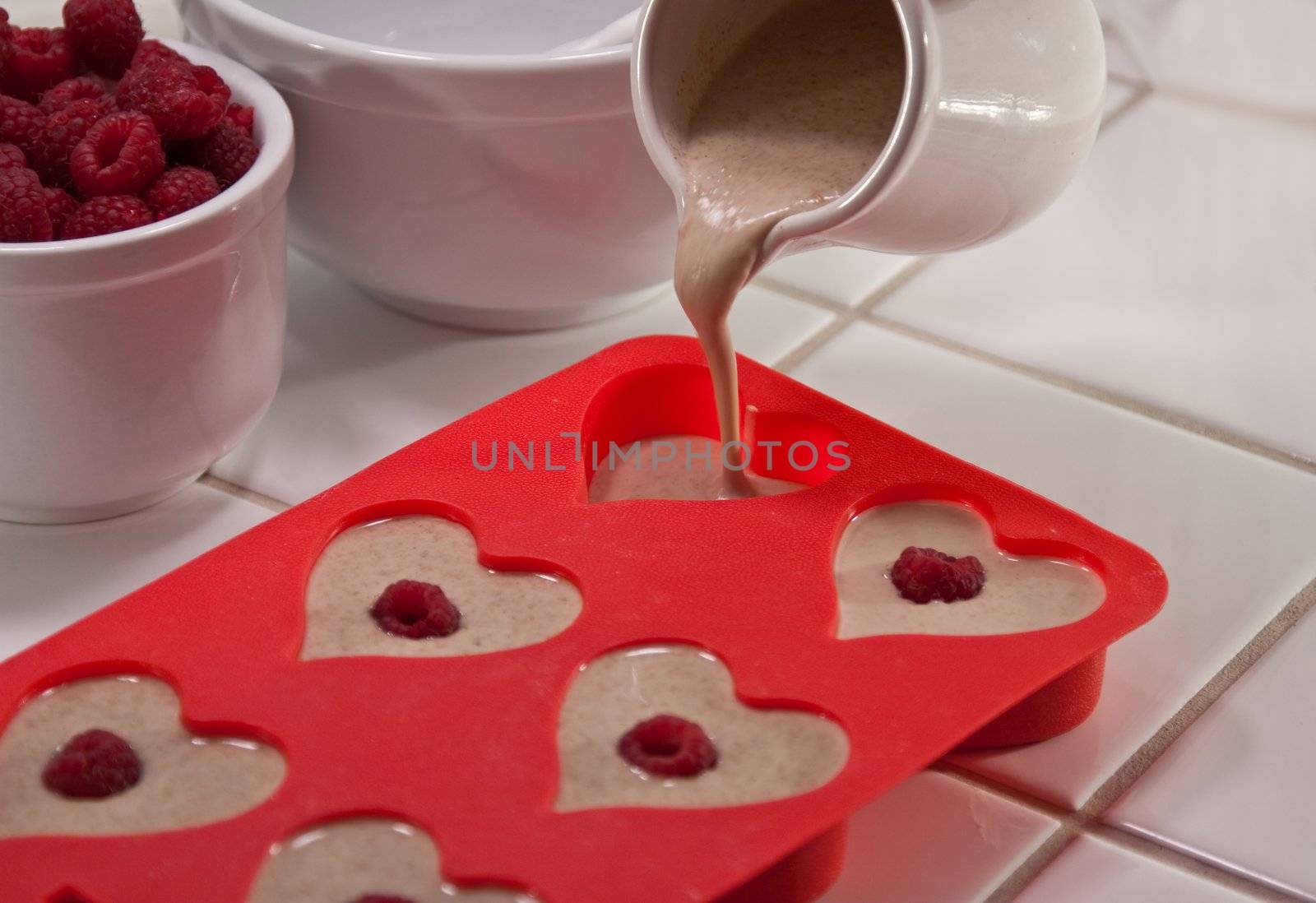 Pouring batter into heart shaped muffin pan and raspberries