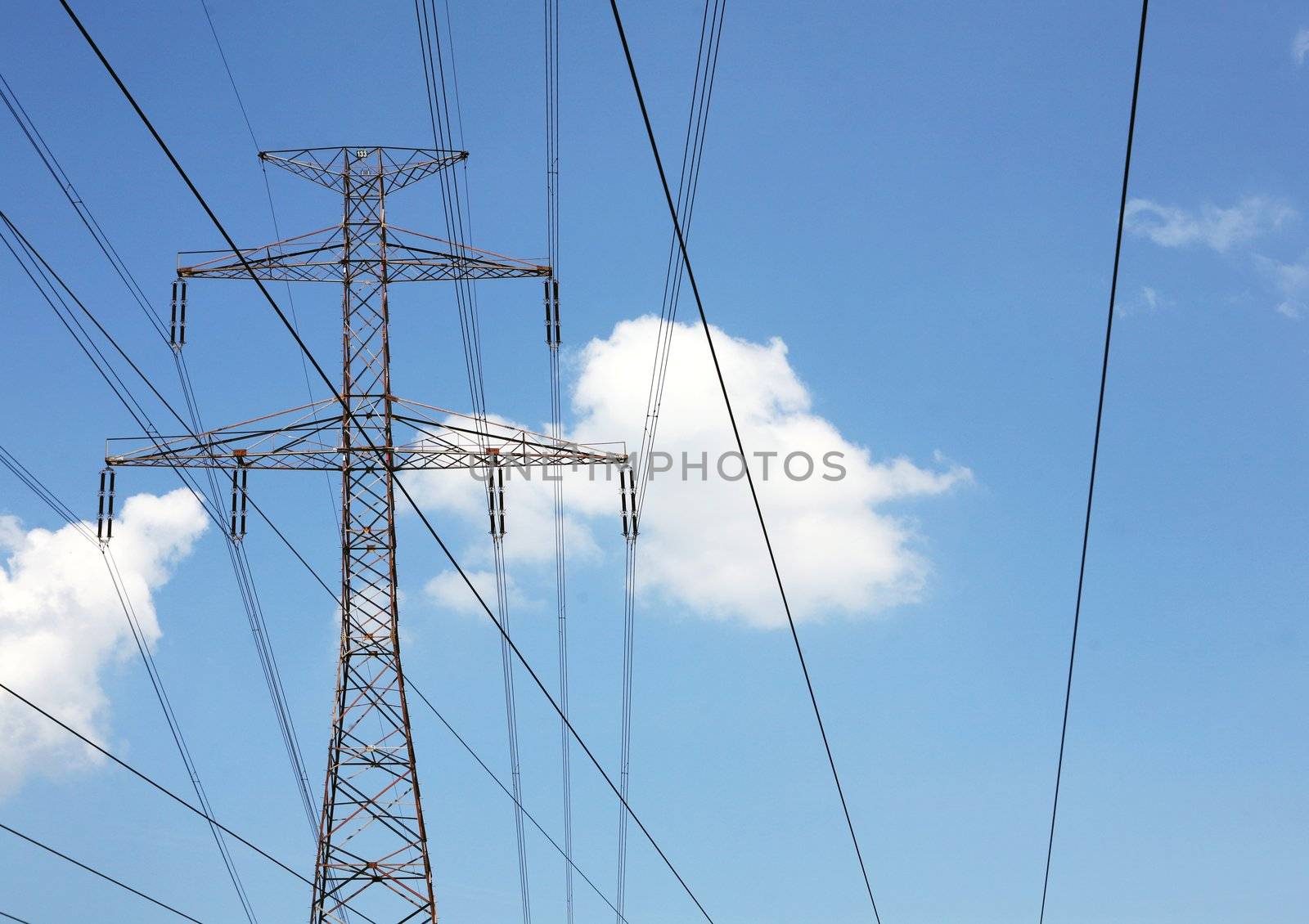 Electric pylons and wires on the cloudy sky