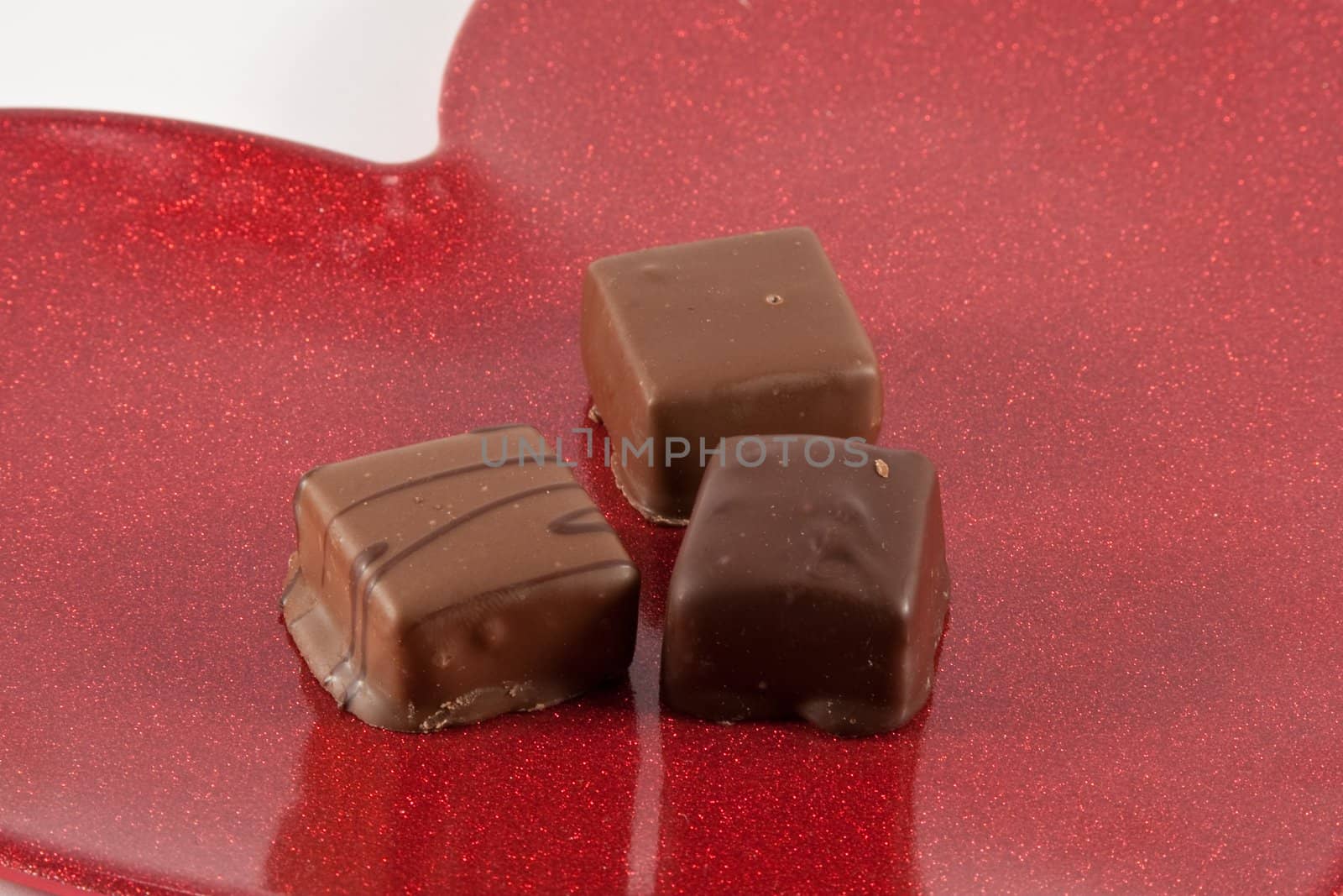 Three small chocolates on red metallic heart dish