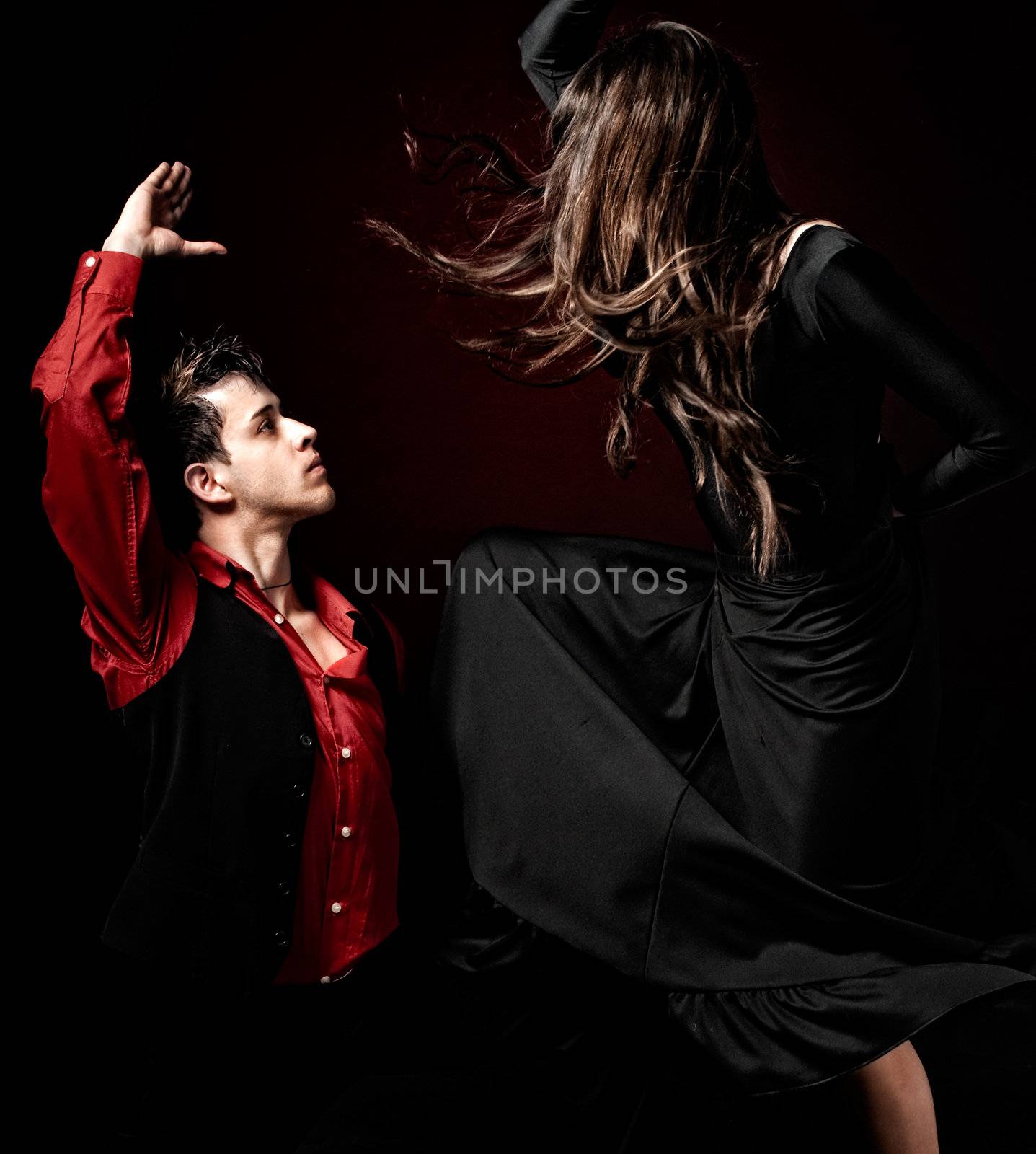 Young couple passion flamenco dancing on red light background. by dgmata
