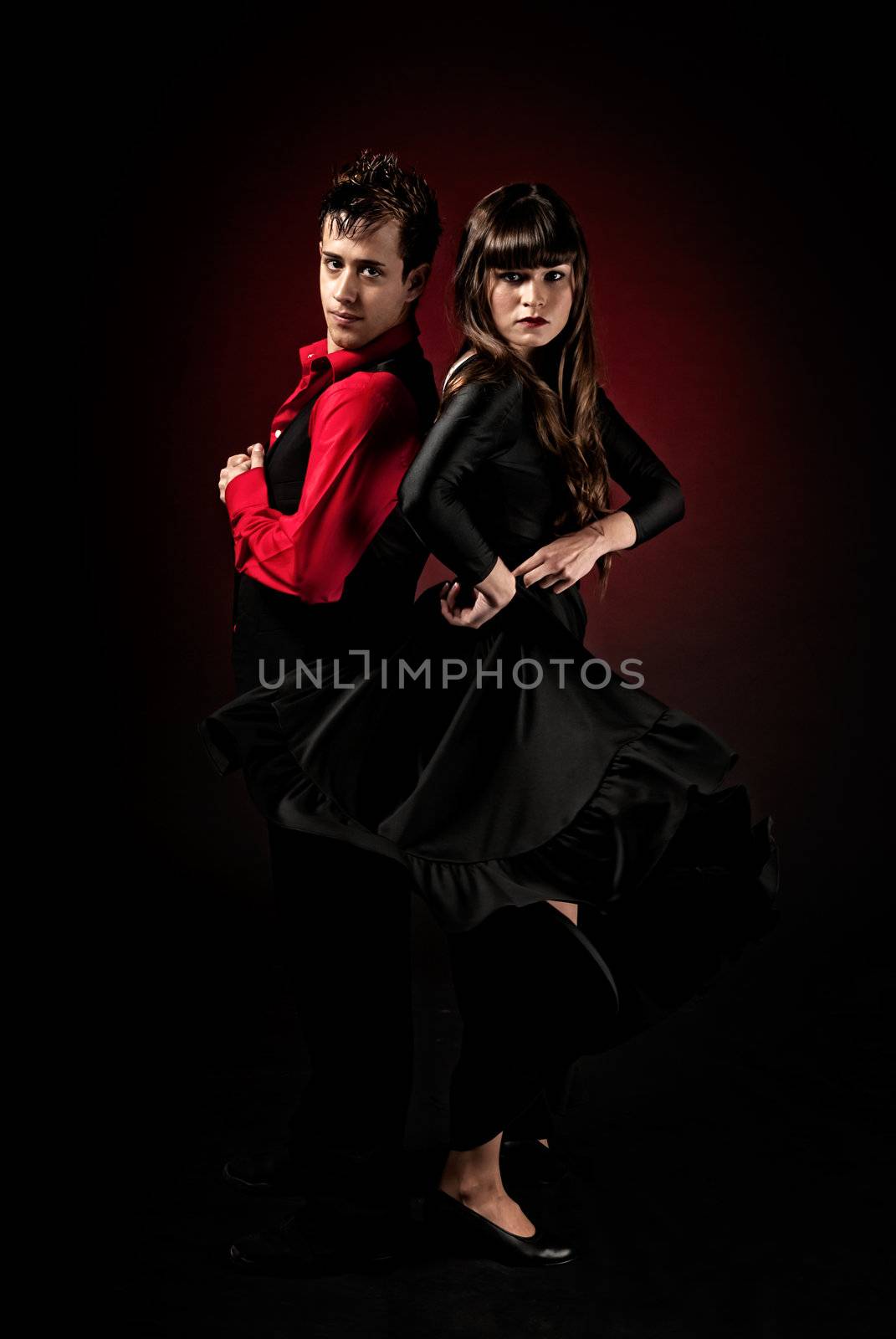 Young couple passion flamenco dancing on red light background. by dgmata