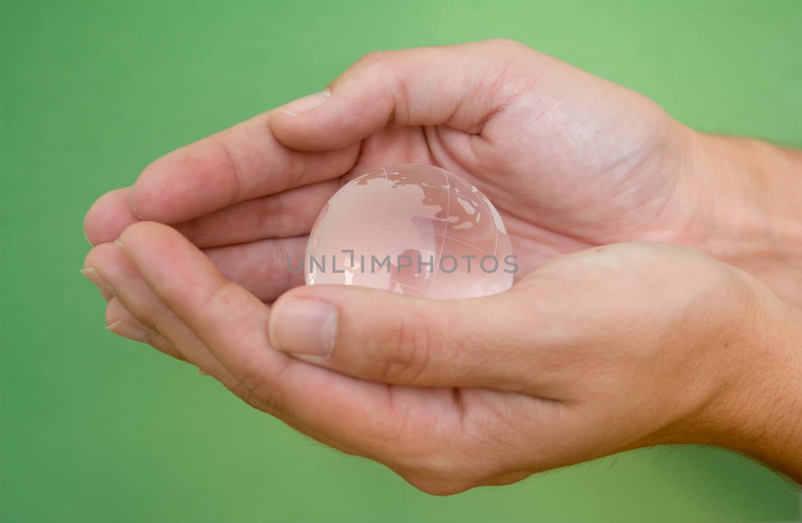 Hands cradling the world shot against a green background