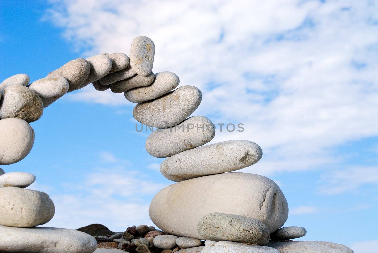 Pile of sea stones in the form of the bridge and the blue sky