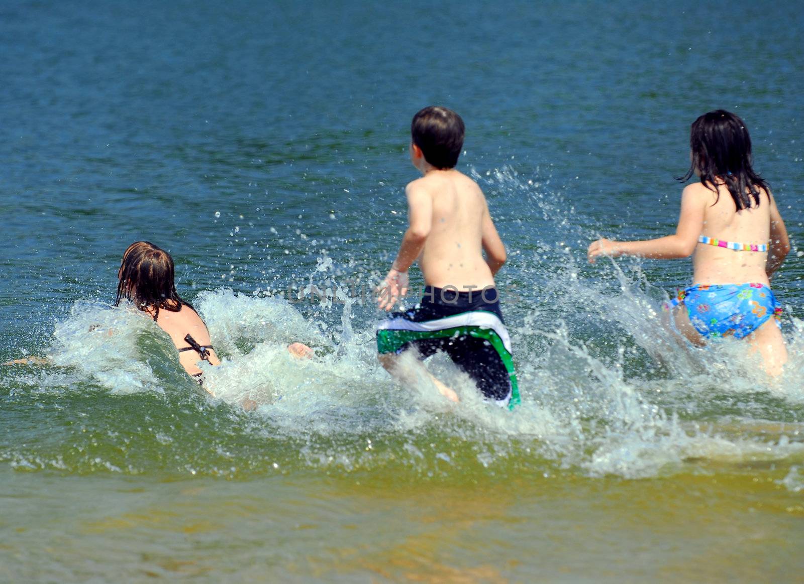 Group of young children running into water at the beach