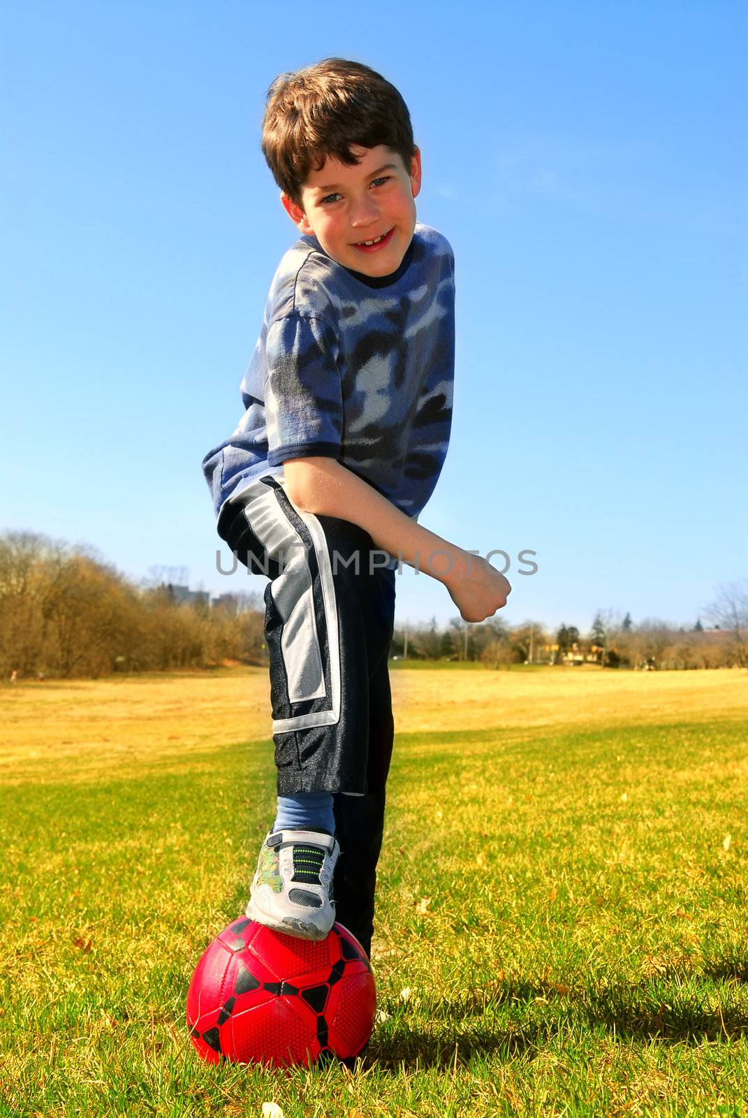 Portrait of a young boy with a red soccer ball outside