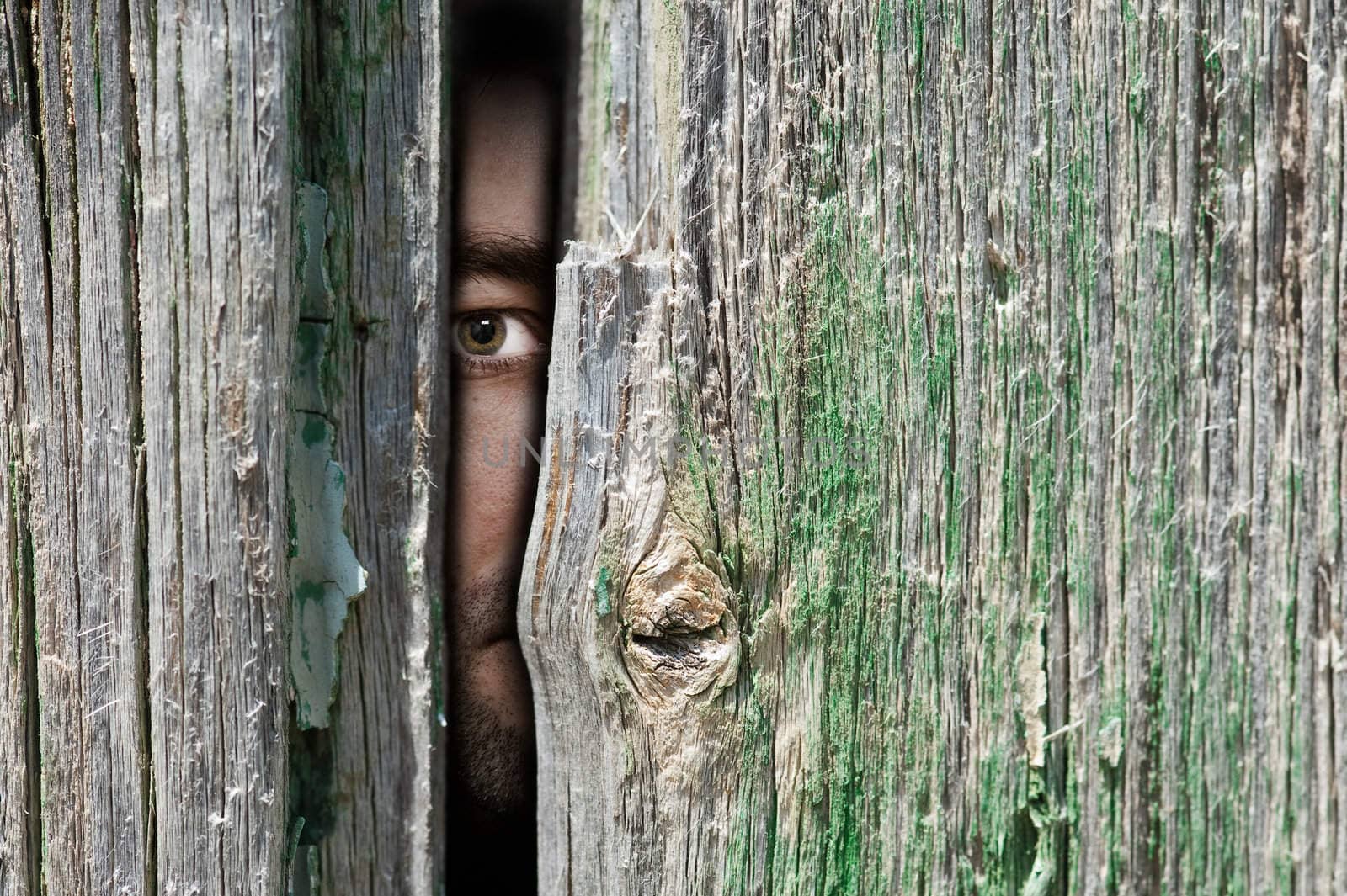 Male person hide behind a wooden wall