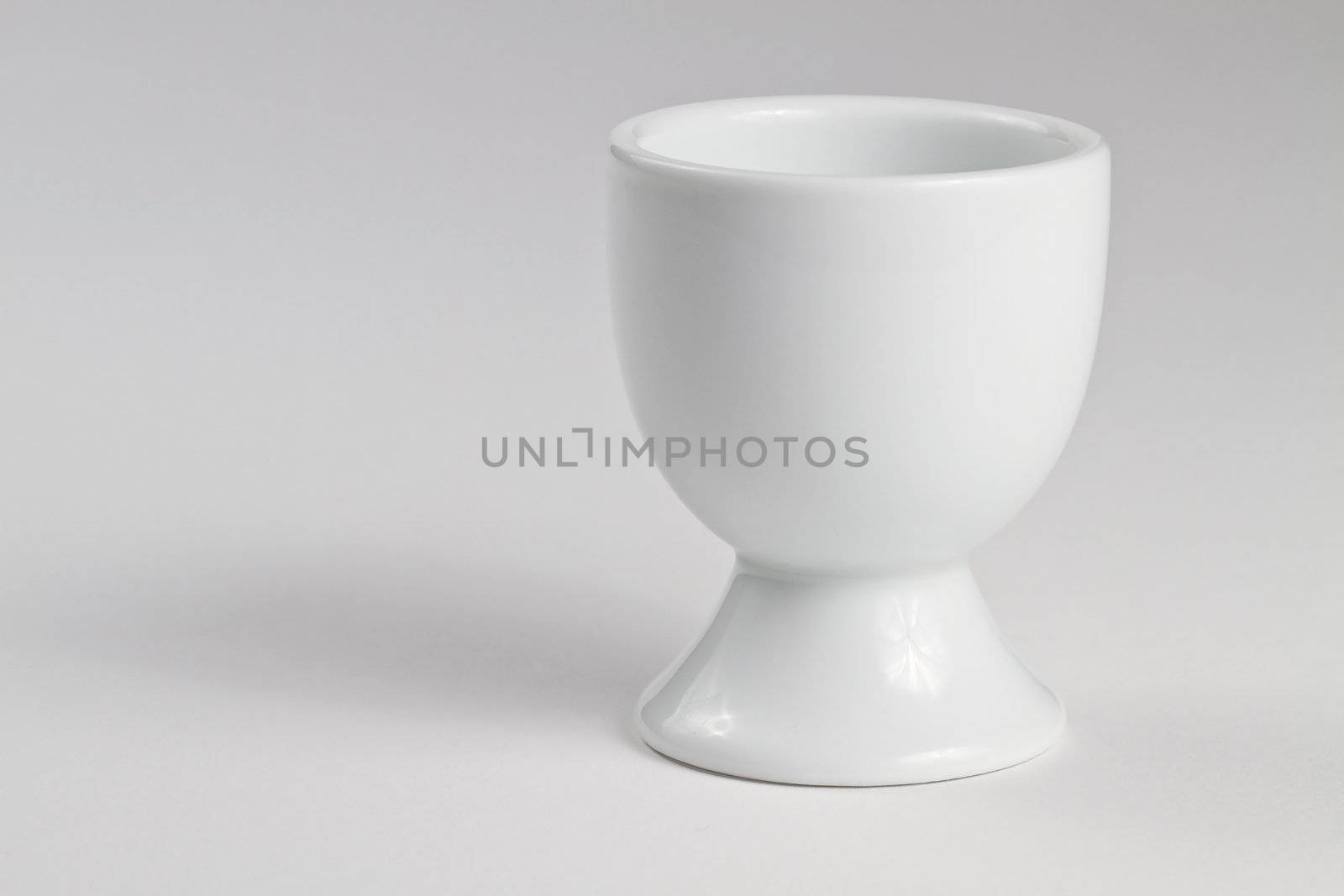 one empty white egg cup on white background