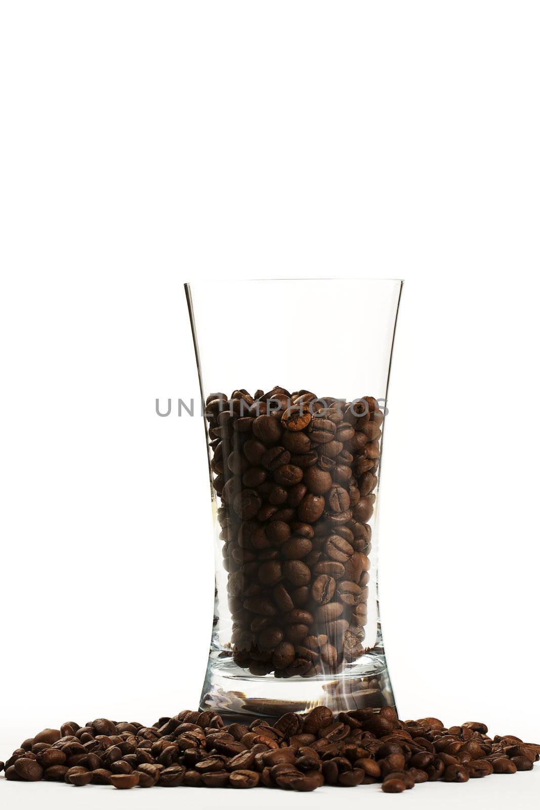 some coffee beans in a glass surrounded by coffee beans