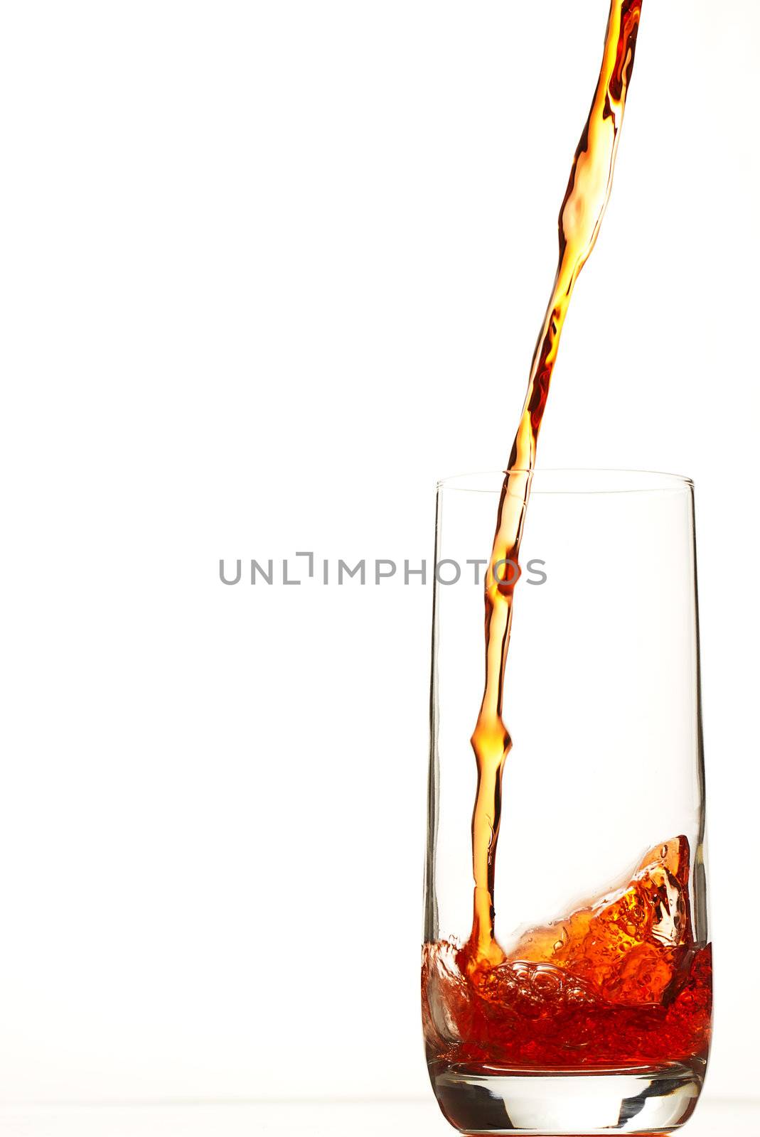 red liquid pouring in glass on white background