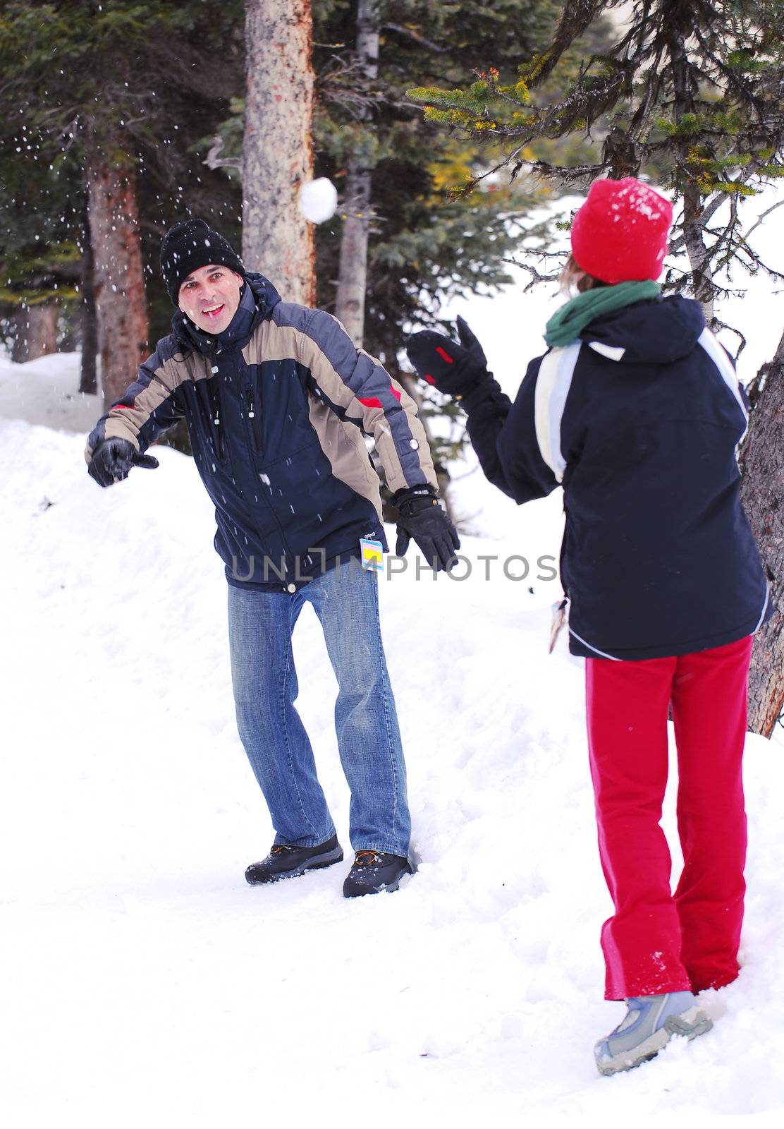 Father and chid throwing snowballs at winter park