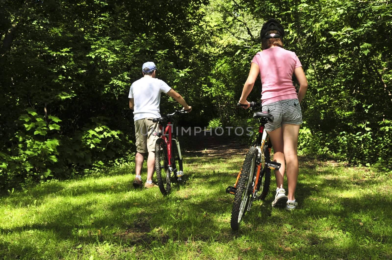 Teenage girl and her father with bicycles in summer park