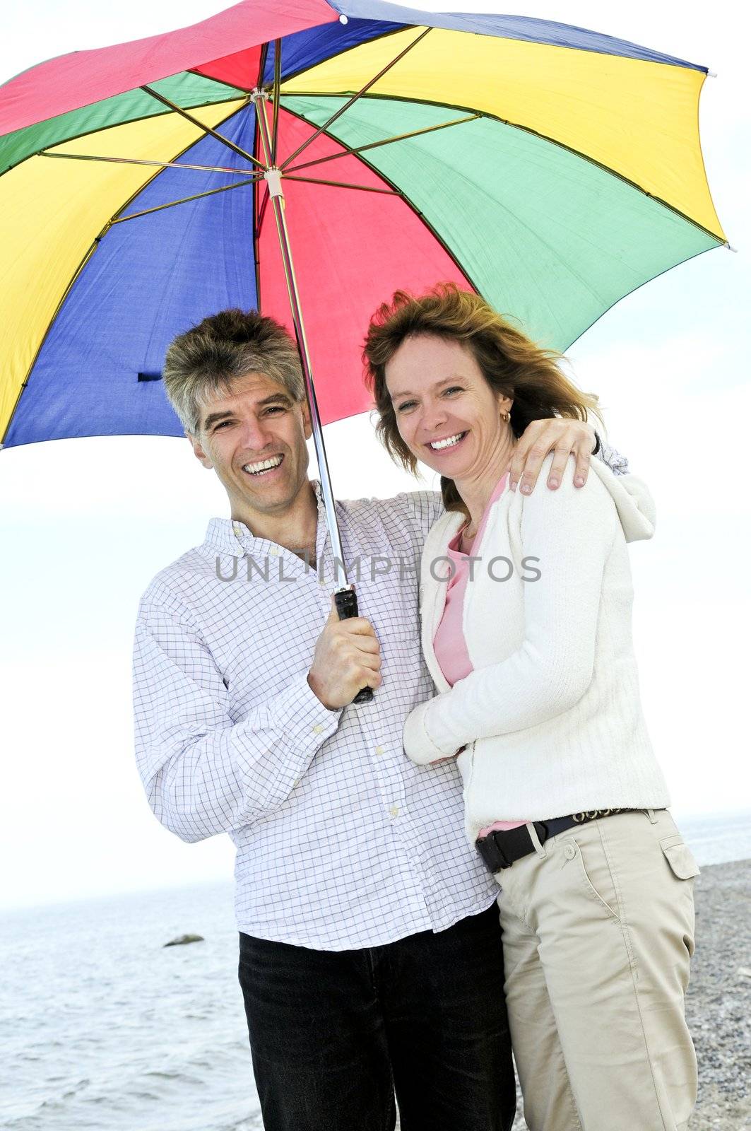 Happy mature couple with umbrella by elenathewise