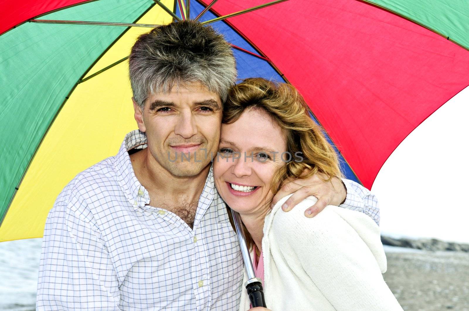Happy mature couple with umbrella by elenathewise