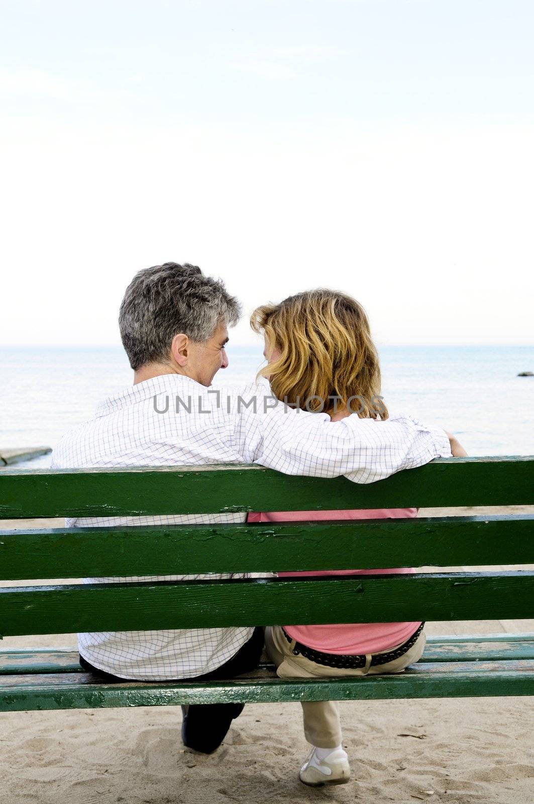 Mature romantic couple on a bench on seashore