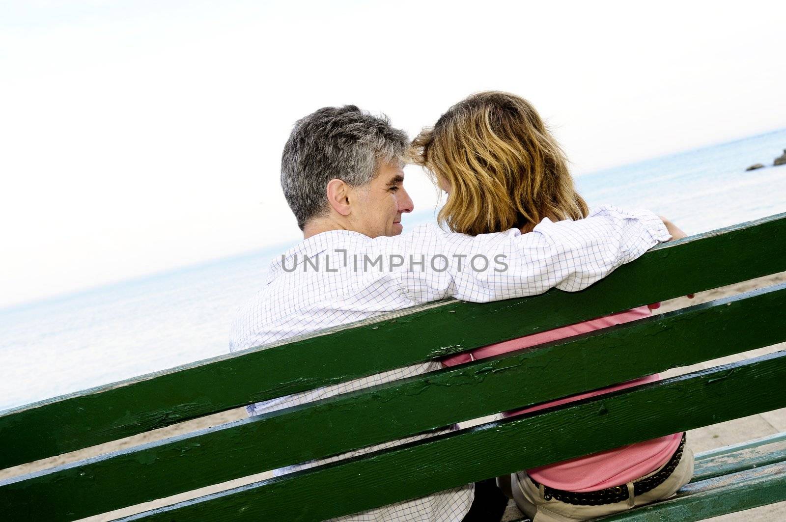 Mature romantic couple on a bench on seashore