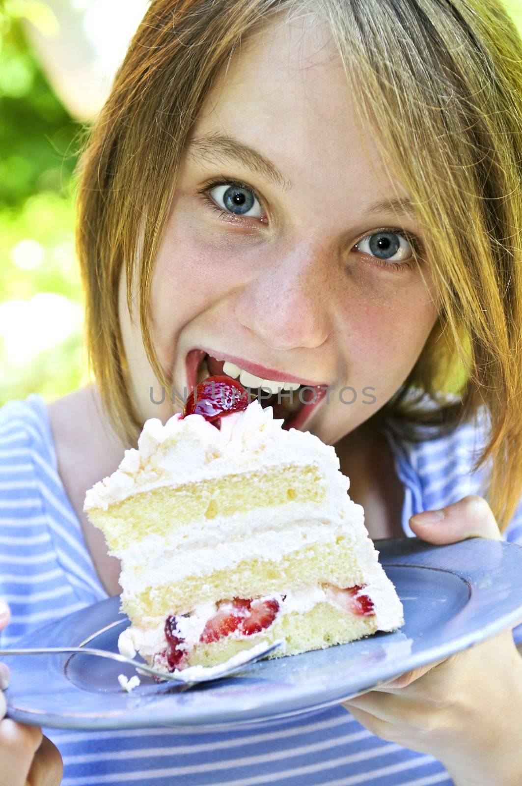 Teenage girl eating a piece of strawberry cake