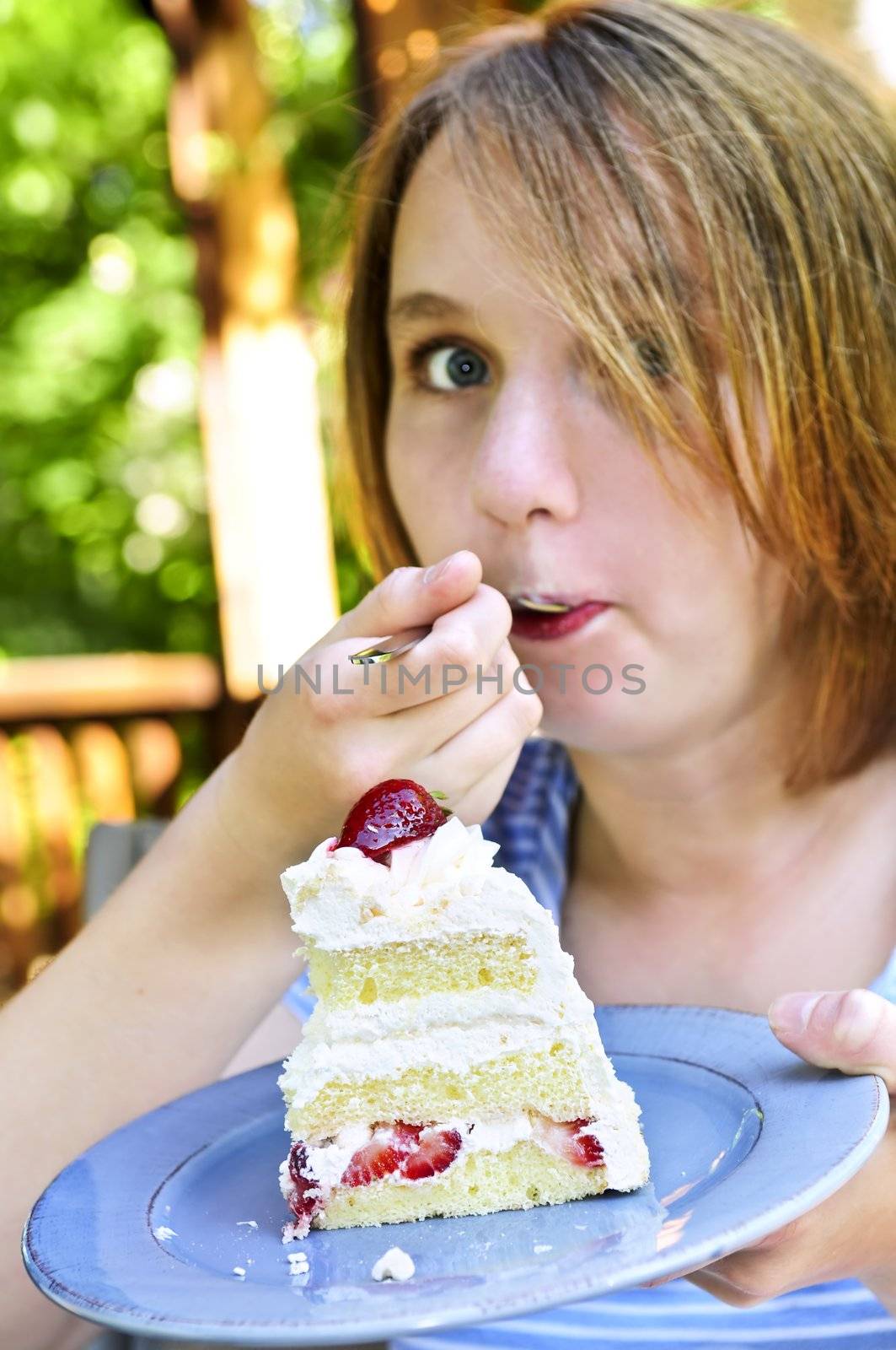 Teenage girl eating a piece of strawberry cake