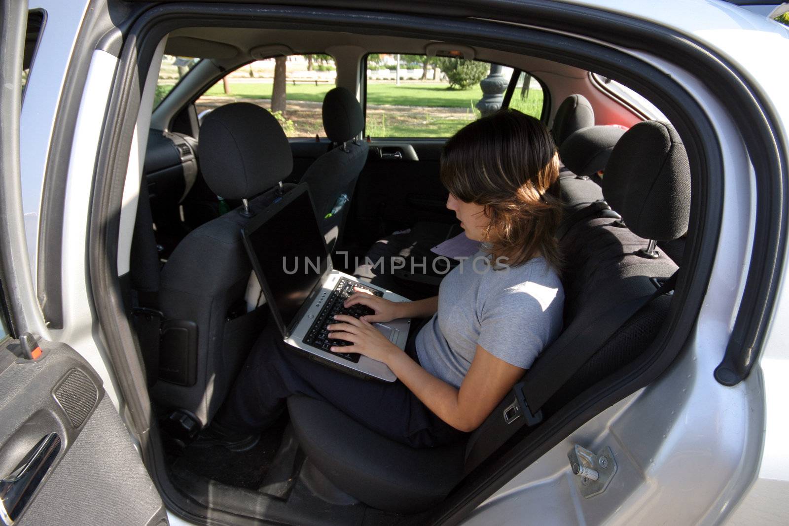 woman working on a laptop on the car