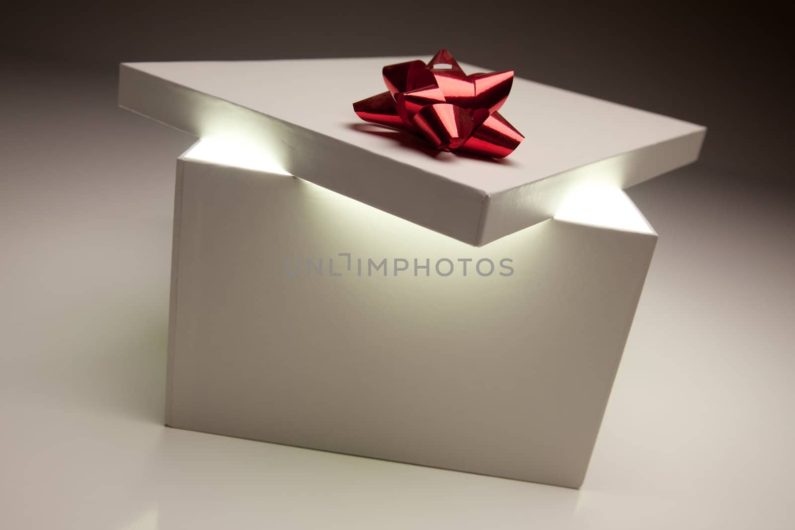 Gift Box with Red Bow Lid Revealing Very Bright Contents on a Gradated Background.