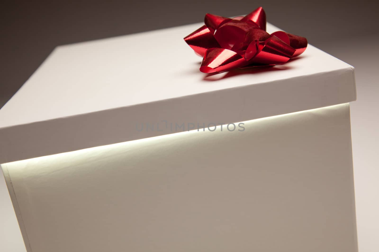 Gift Box with Red Bow Lid Revealing Very Bright Contents on a Gradated Background.