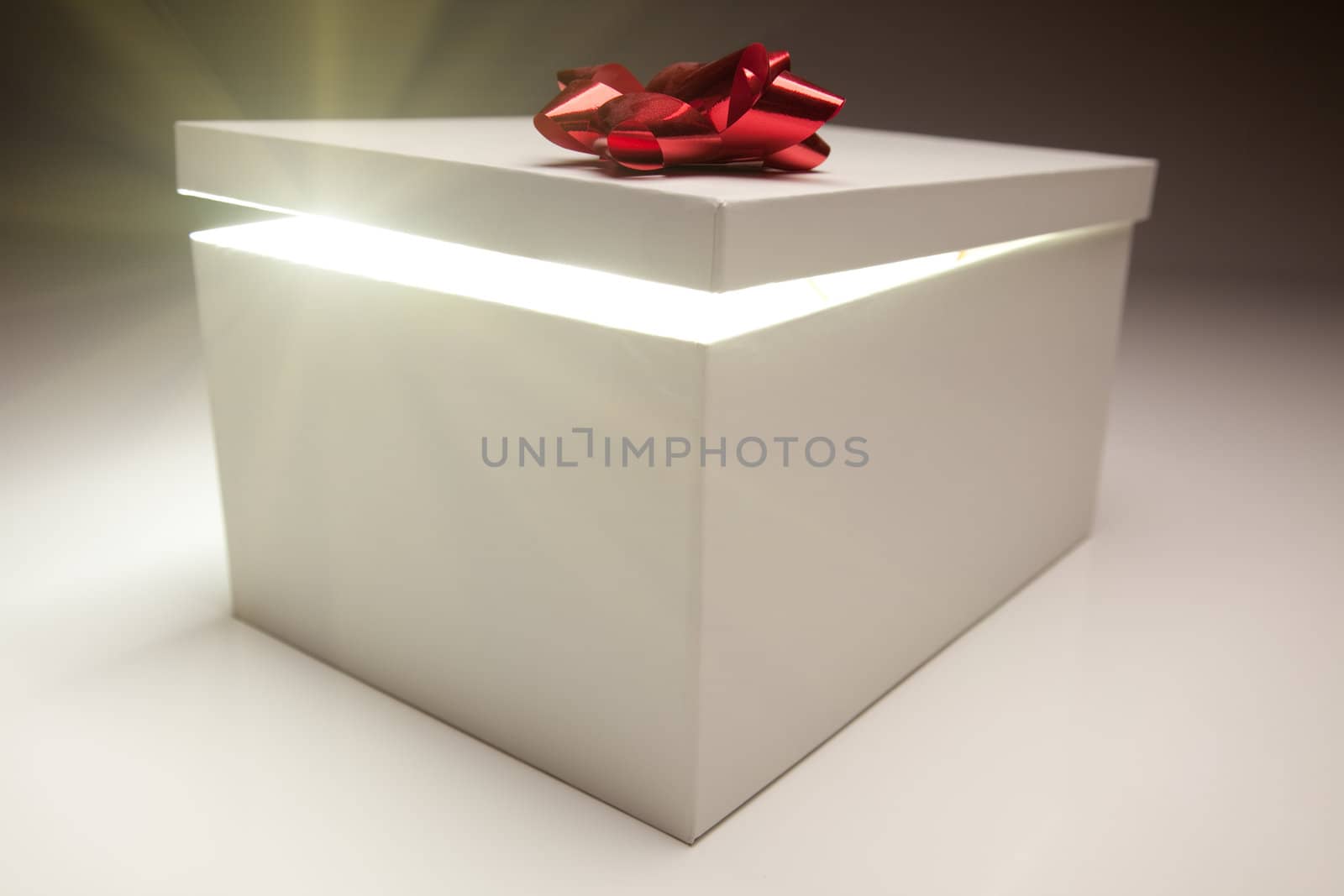 Gift Box with Red Bow Lid Revealing Very Bright Contents on a Gradated Background.