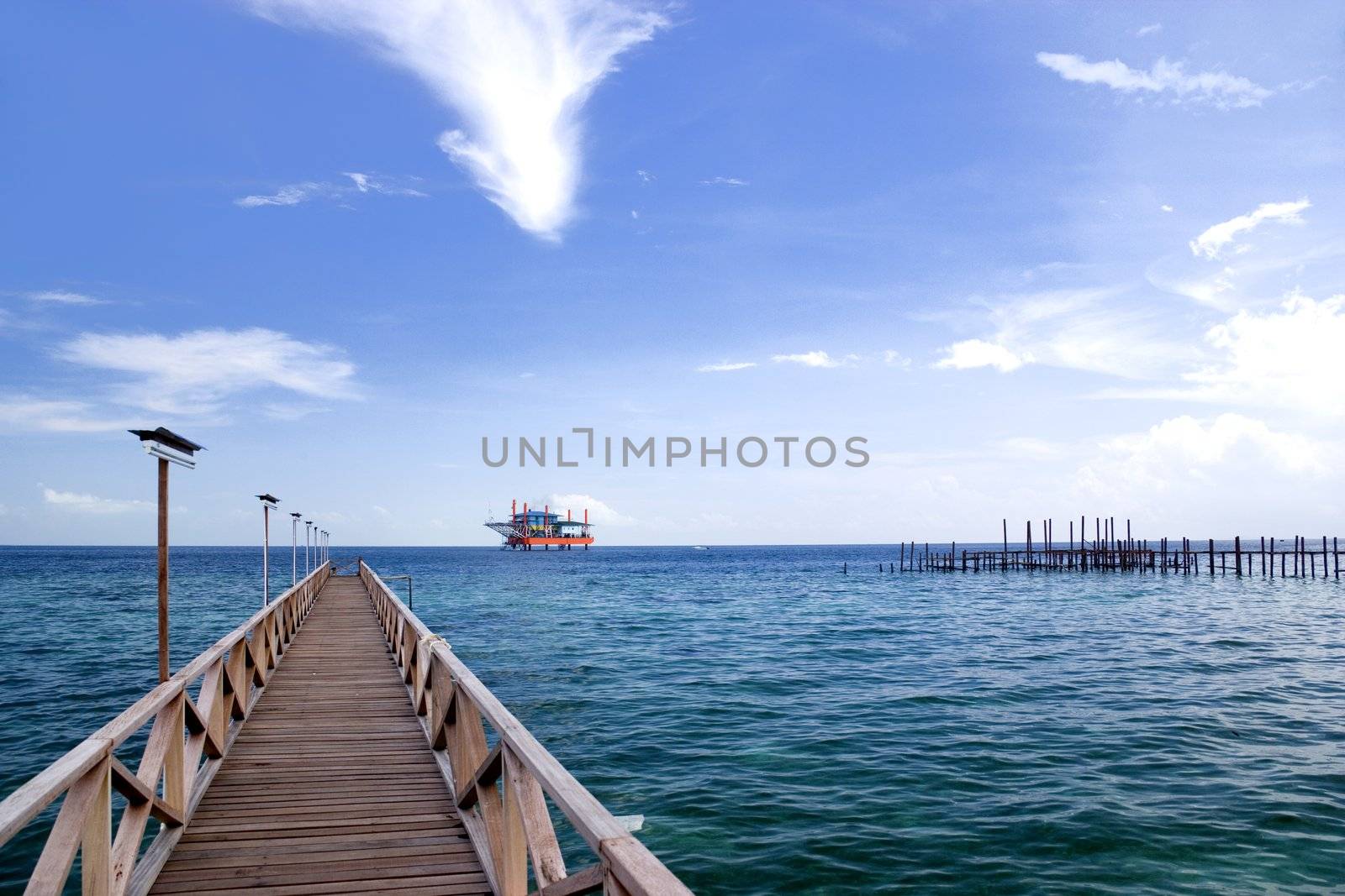 Image of a jetty against a backdrop of a beautiful sea, sky and an oil rig in Malaysia.