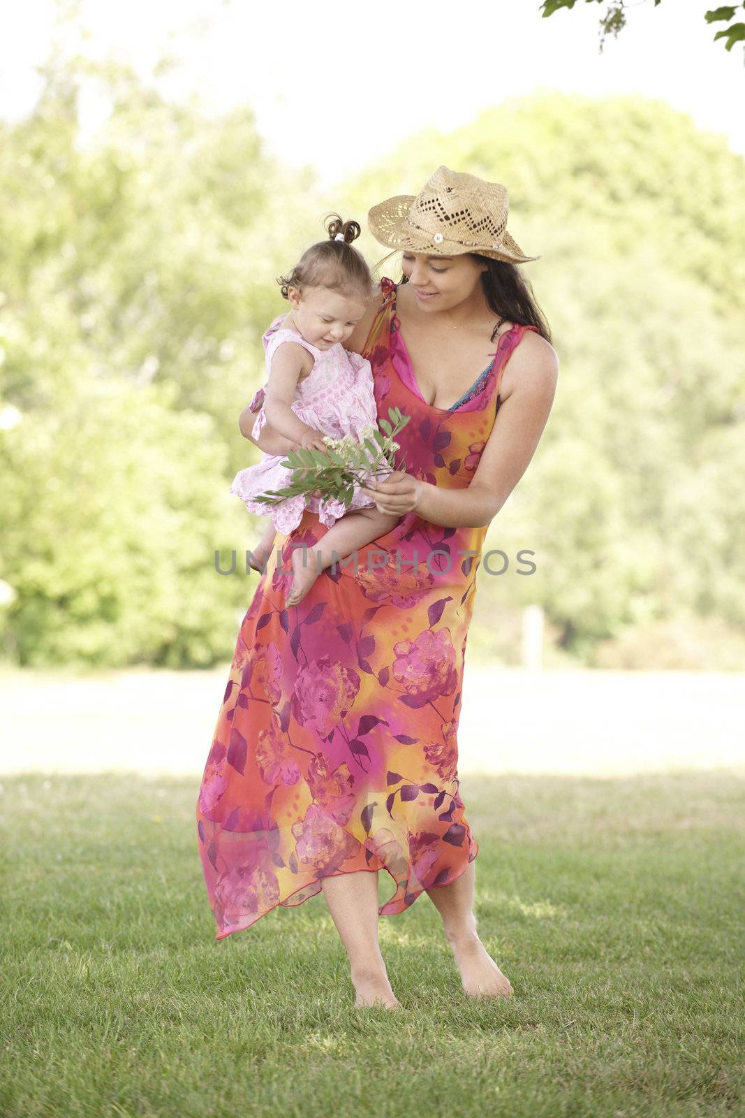 mother holding her daughter while out for a walk in the park