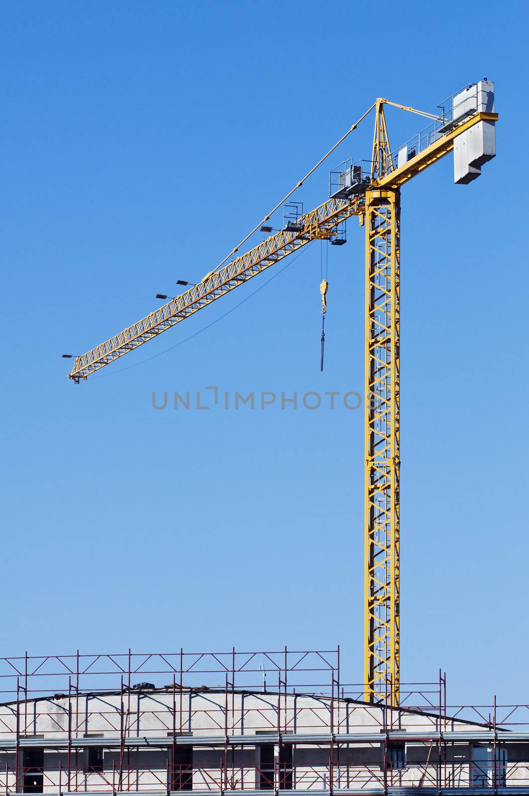 Yellow crane in a contruction site abd a building with scaffolding