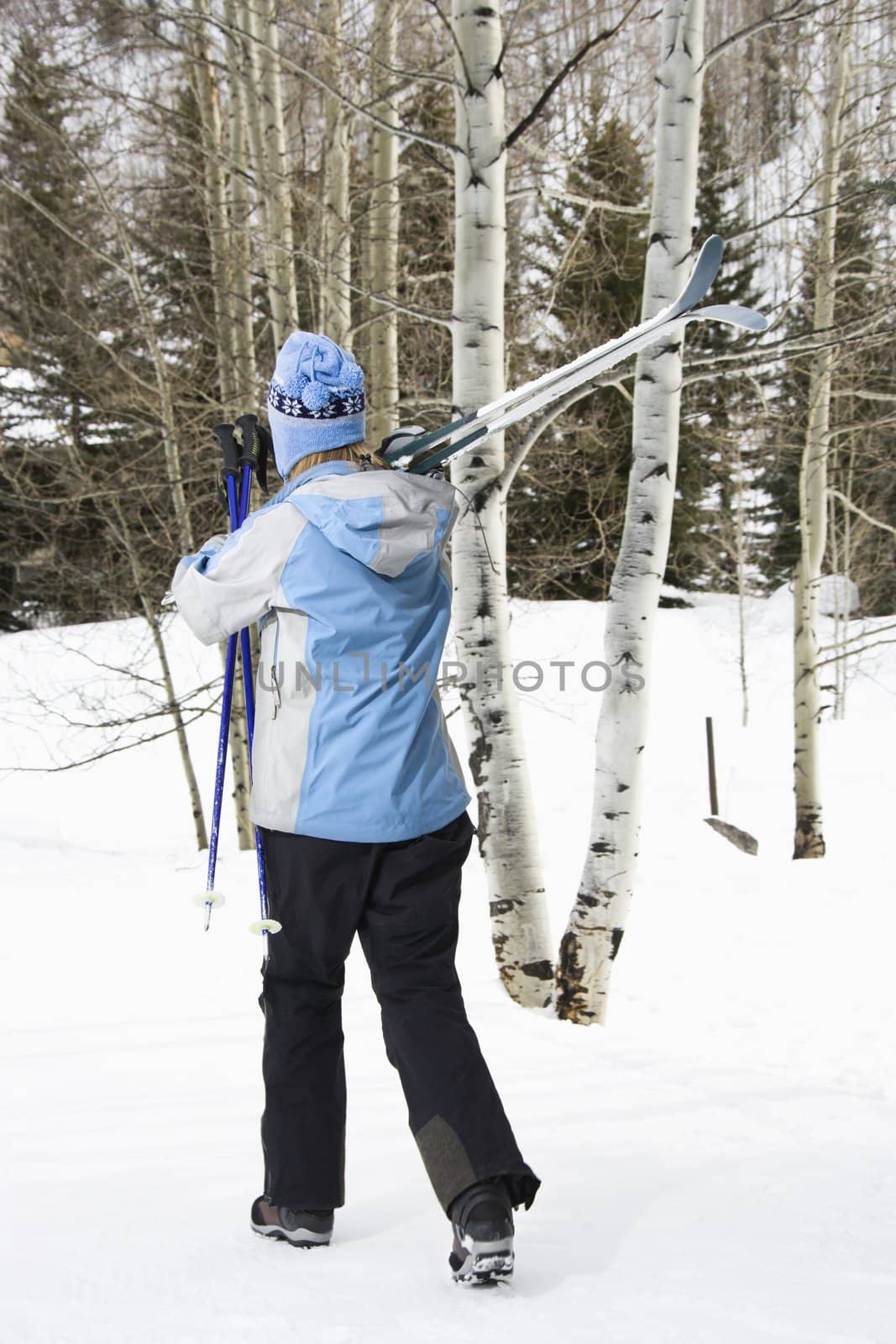 Female walking with skis. by iofoto