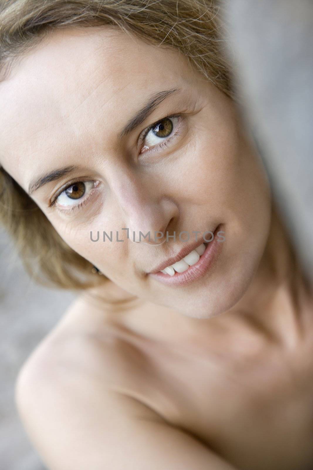 Mid adult Caucasian nude woman smiling at viewer.