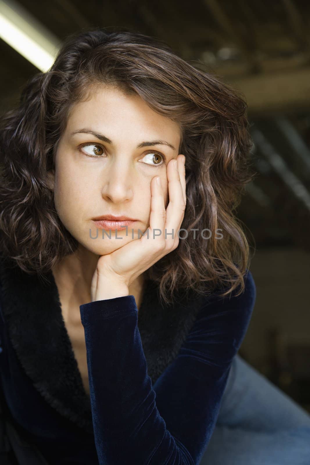 Portrait of pretty mid adult Caucasian woman with head on hand looking out to side.