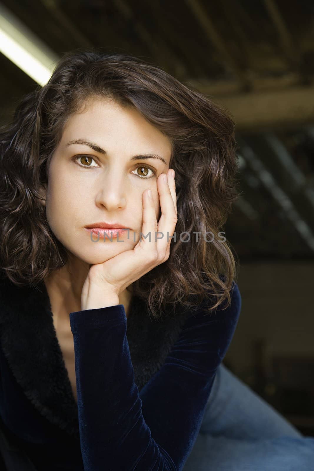 Portrait of pretty mid adult Caucasian woman with head on hand making eye contact.