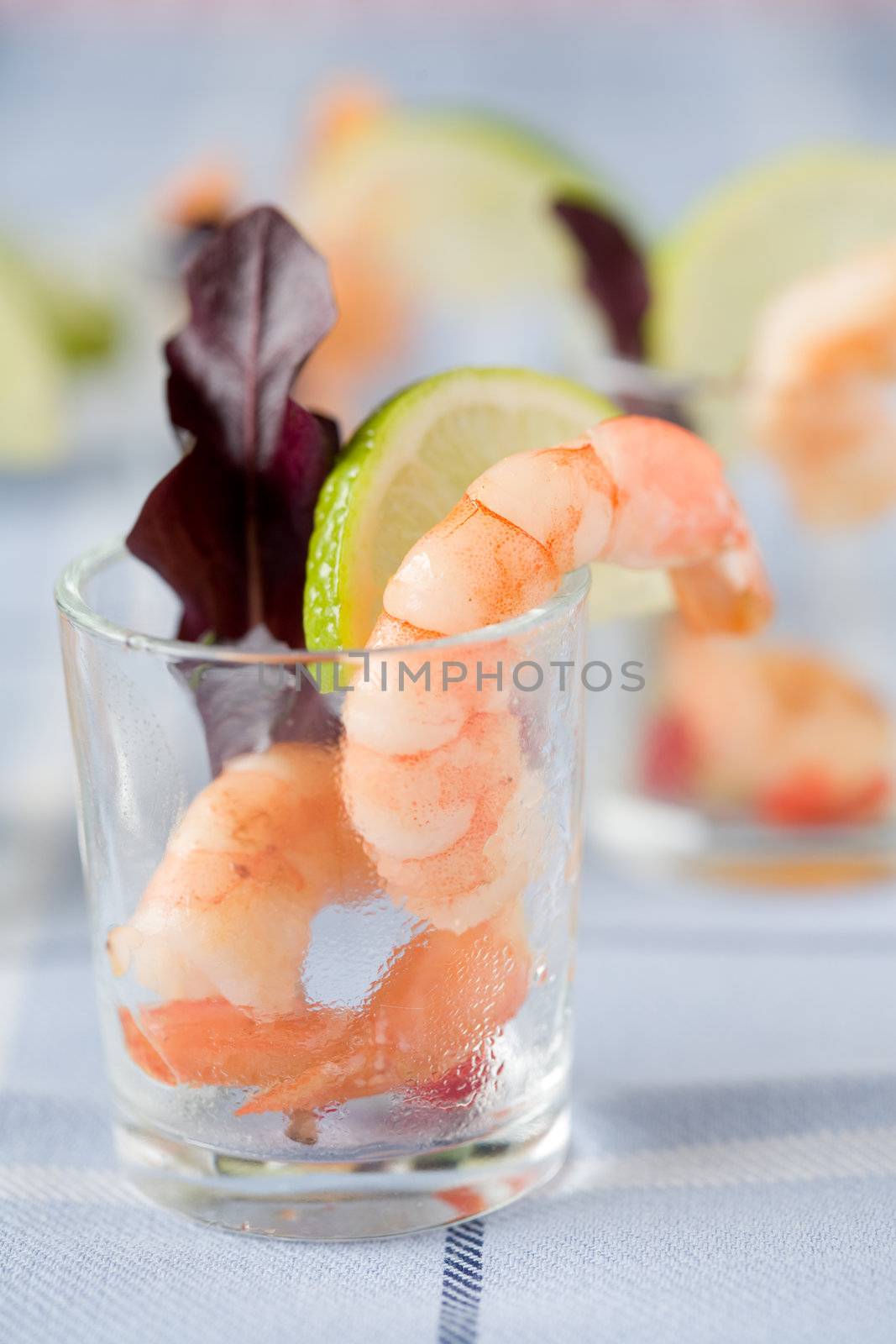 Small appetizer served in a glass with shrimps and lemon
