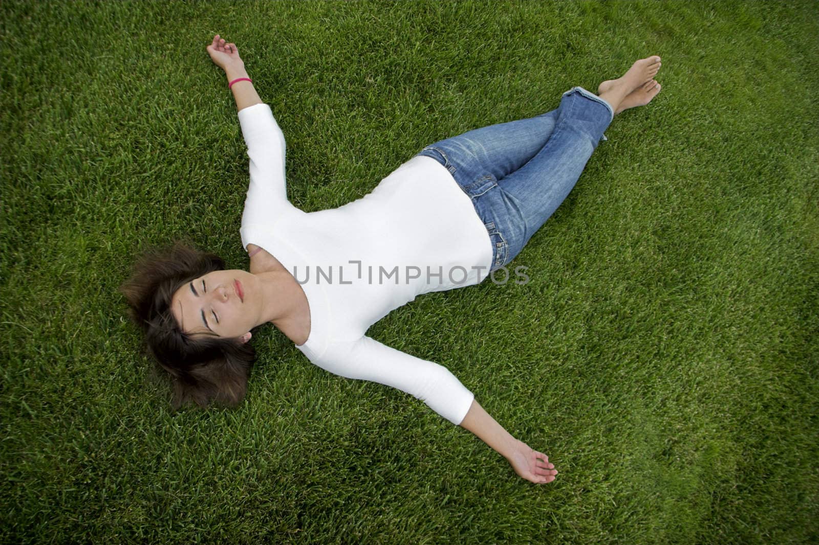 Beautiful young woman lying on the grass 