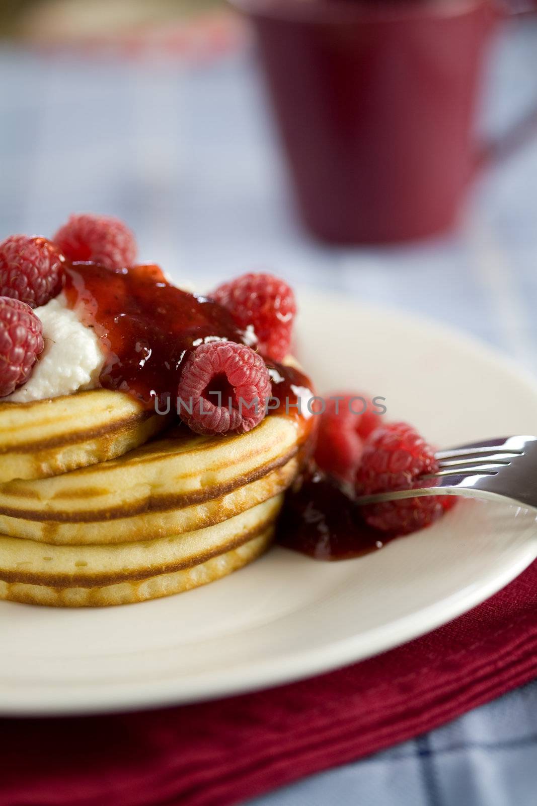 Delicious small american pancakes with raspberries and cream