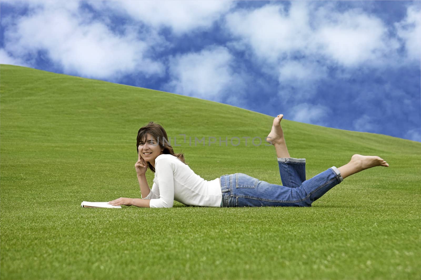 Beautiful woman lying on the grass and reading