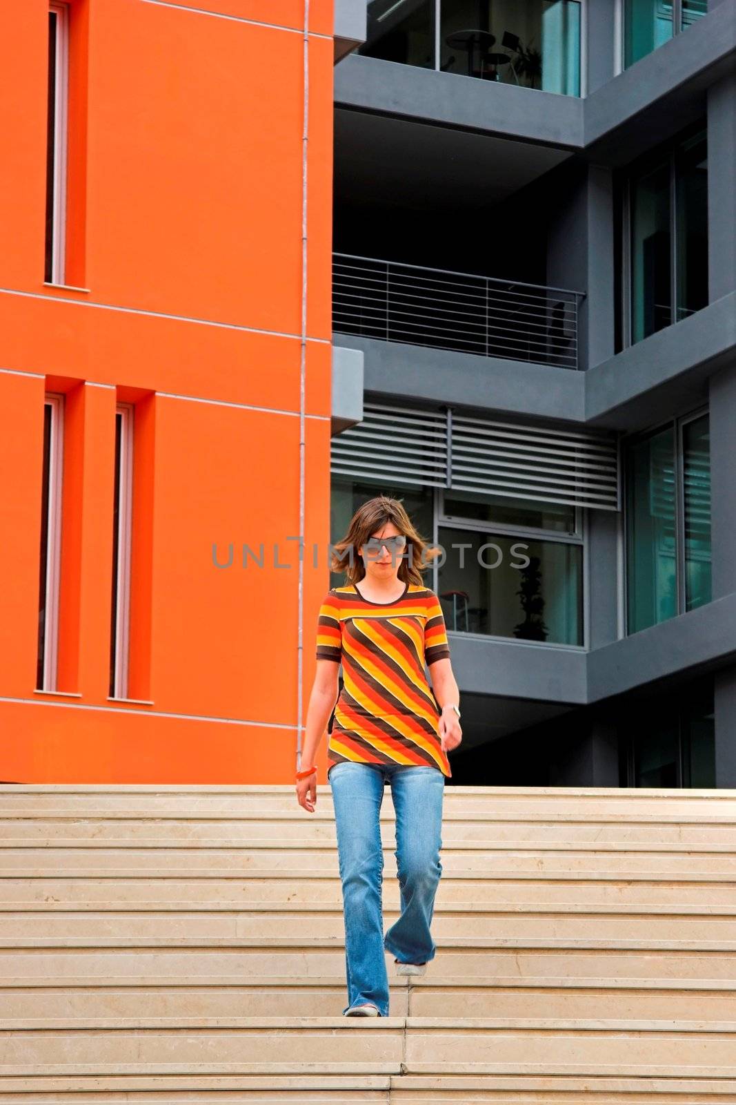 A young woman walking through the stairs of modern building