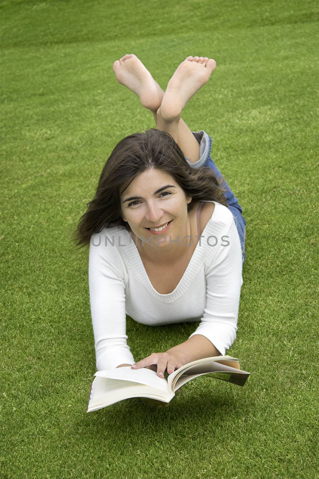 Beautiful woman with a happy face and reading on the grass