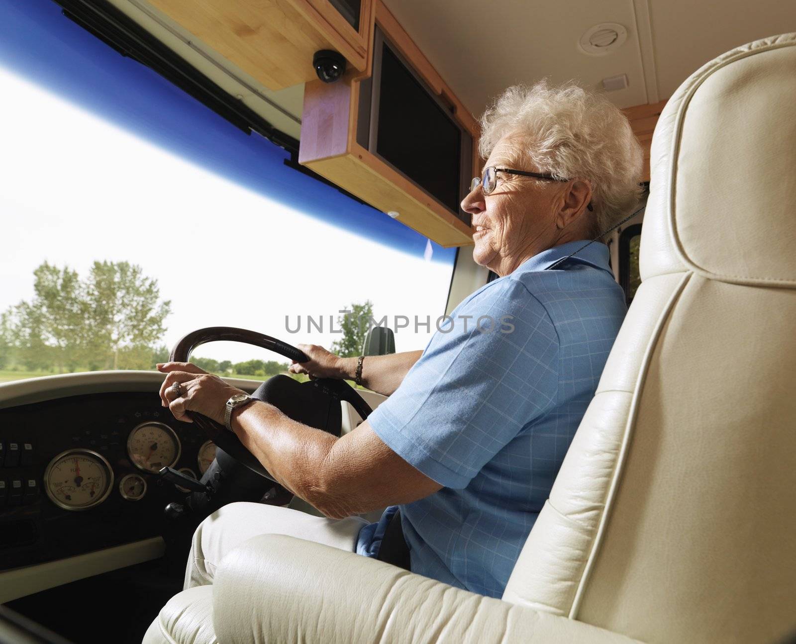 Senior adult woman driving RV and smiling.
