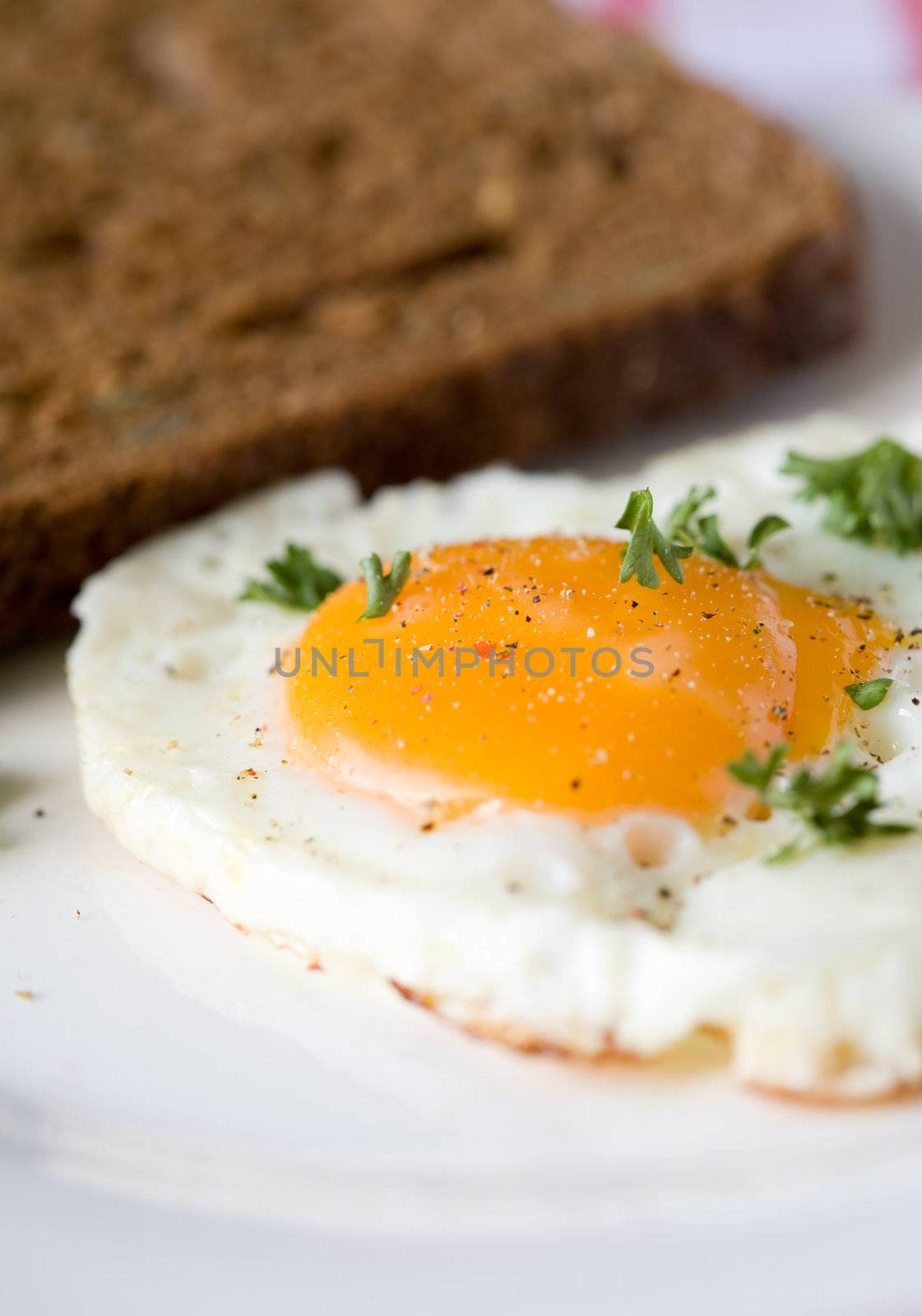 Fried egg with whole eggyolk and sandwich in background
