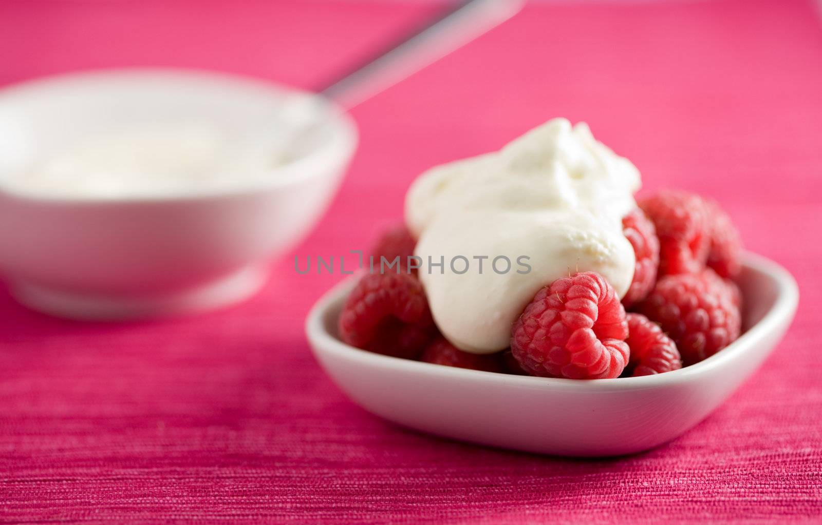 Small bowl filled with raspberries and whipped cream