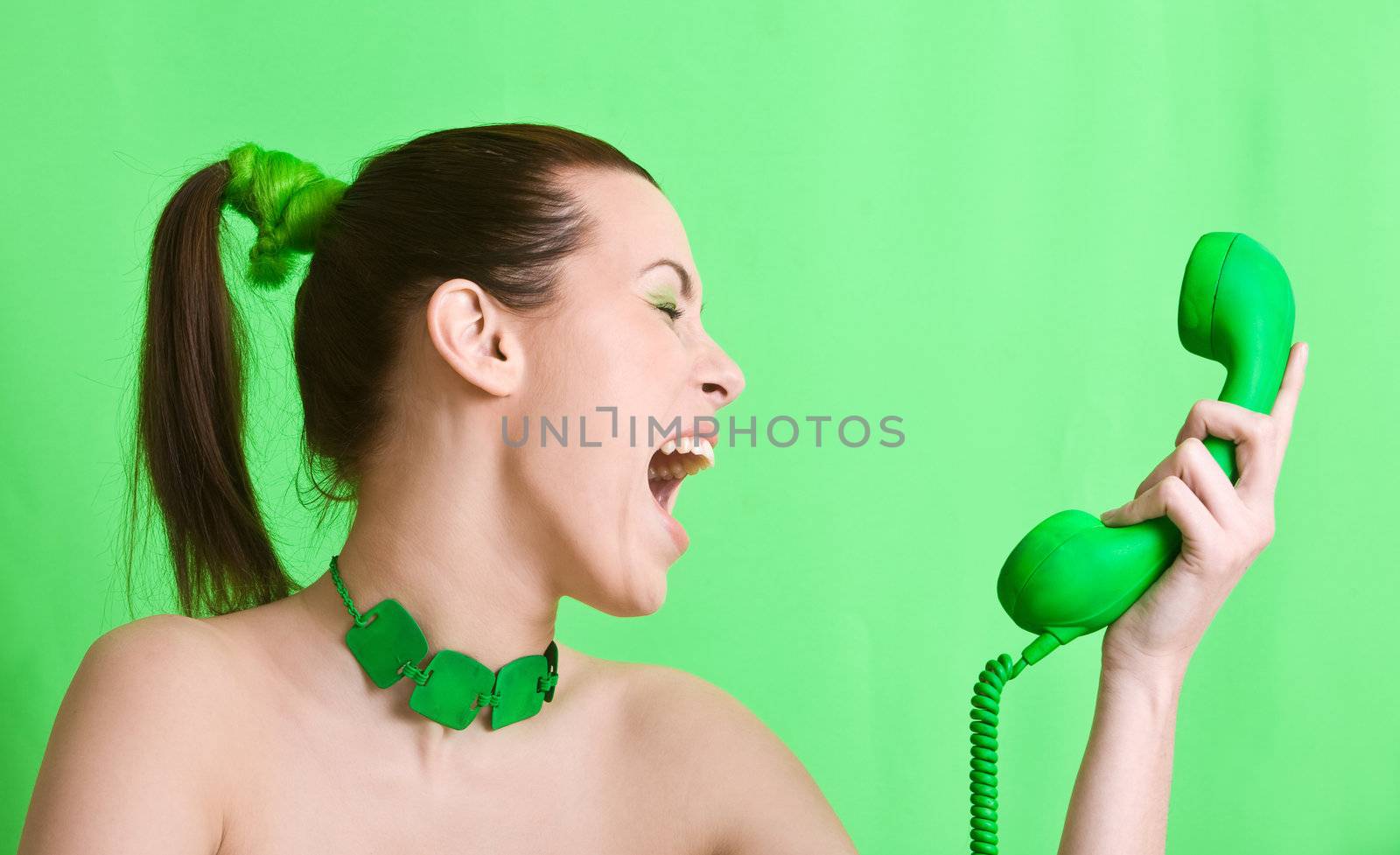 Woman on green background screaming into the green phone