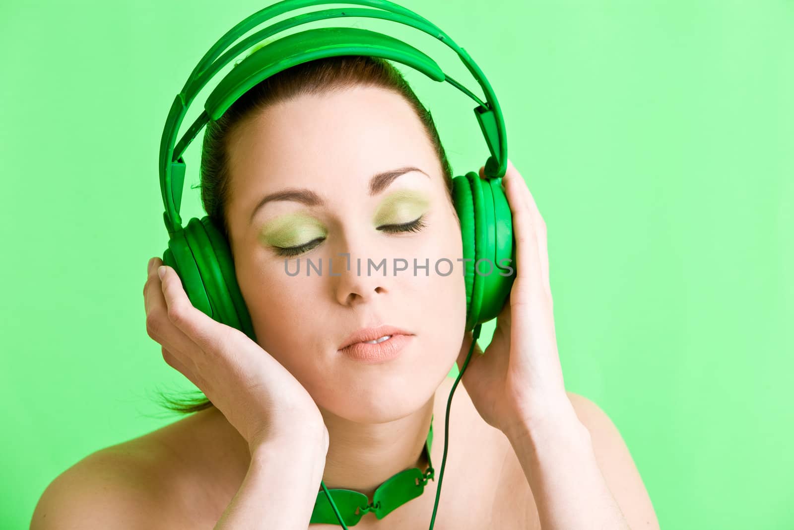 Beautiful brunette with green headphones listening to music
